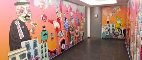 A brightly decorated hallway with colorful murals on the walls, including whimsical characters and buildings.