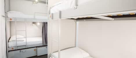 Habitación con literas, un armario pequeño y una ventana con cortinas.