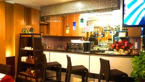 A bar area with wooden furniture, shelves with bottles, and a television screen.