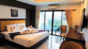 A hotel room with a large bed, a desk, a chair, and a view of the city through the window.