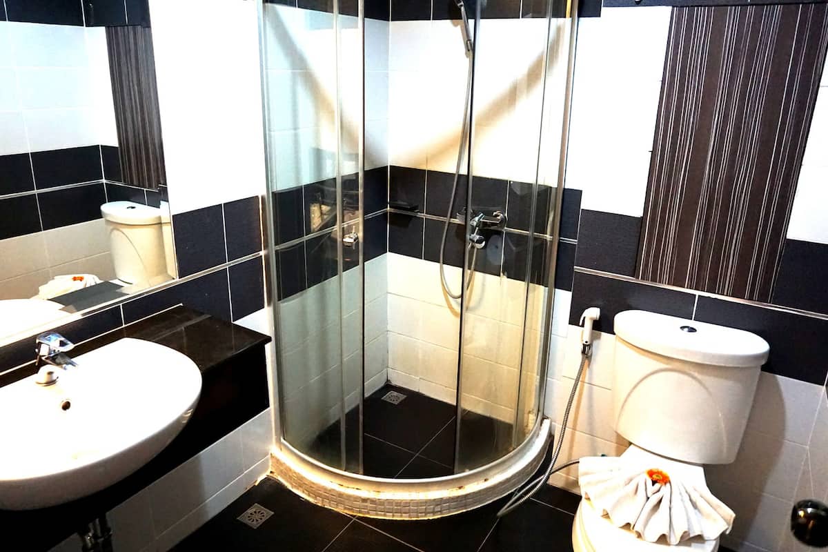 A modern bathroom with a glass-enclosed shower, a round sink, and a toilet.