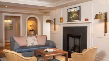 A living room with a fireplace, a sofa, two armchairs, a coffee table, and a rug.
