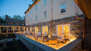 A stone exterior with a covered outdoor seating area and a stone wall. - Boar's Head Resort (Charlottesville)