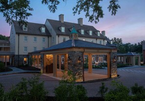 A hotel with a stone pavilion, multiple windows, and a large building in the background.