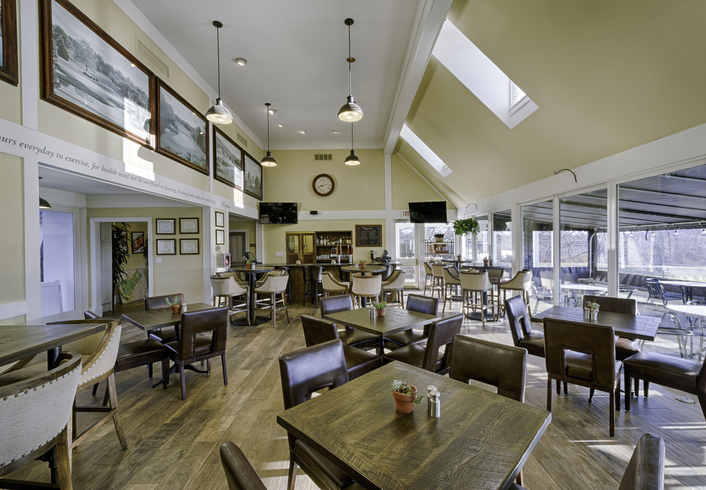 A spacious dining area with high ceilings, pendant lighting, and large windows offering views of the outdoors.