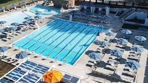 A large outdoor swimming pool with multiple lanes, surrounded by sun loungers and umbrellas. - Boar's Head Resort (Charlottesville)