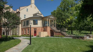 A two-story house with a brick facade, a red door, and a stone pathway leading to the entrance.