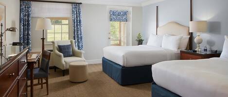 Een hotelkamer met twee bedden, een bureau met stoel, een dressoir en een raam met gordijnen.