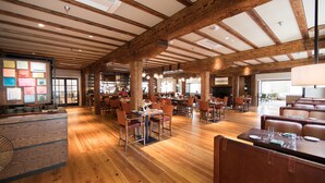 A spacious restaurant with wooden floors and high ceilings, featuring multiple dining areas with tables and chairs. - Boar's Head Resort (Charlottesville)
