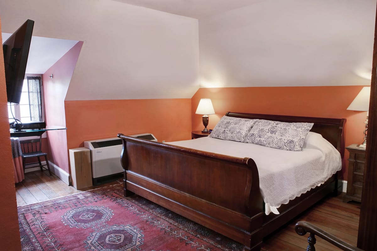 A bedroom with a wooden bed, a desk, and a chair.