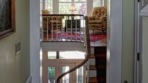 Eine Treppe führt zu einem Balkon mit Geländer, an der Wand hängt ein Feuerlöscher und rechts ist eine Tür zu sehen.