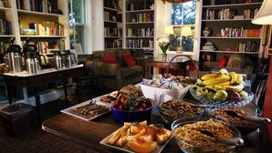 Ein gemütliches Wohnzimmer mit einem Couchtisch voller Snacks, umgeben von Bücherregalen und einer bequemen Sitzecke.