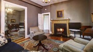 Ein Wohnzimmer mit Kamin, Fernseher und Klavier.
