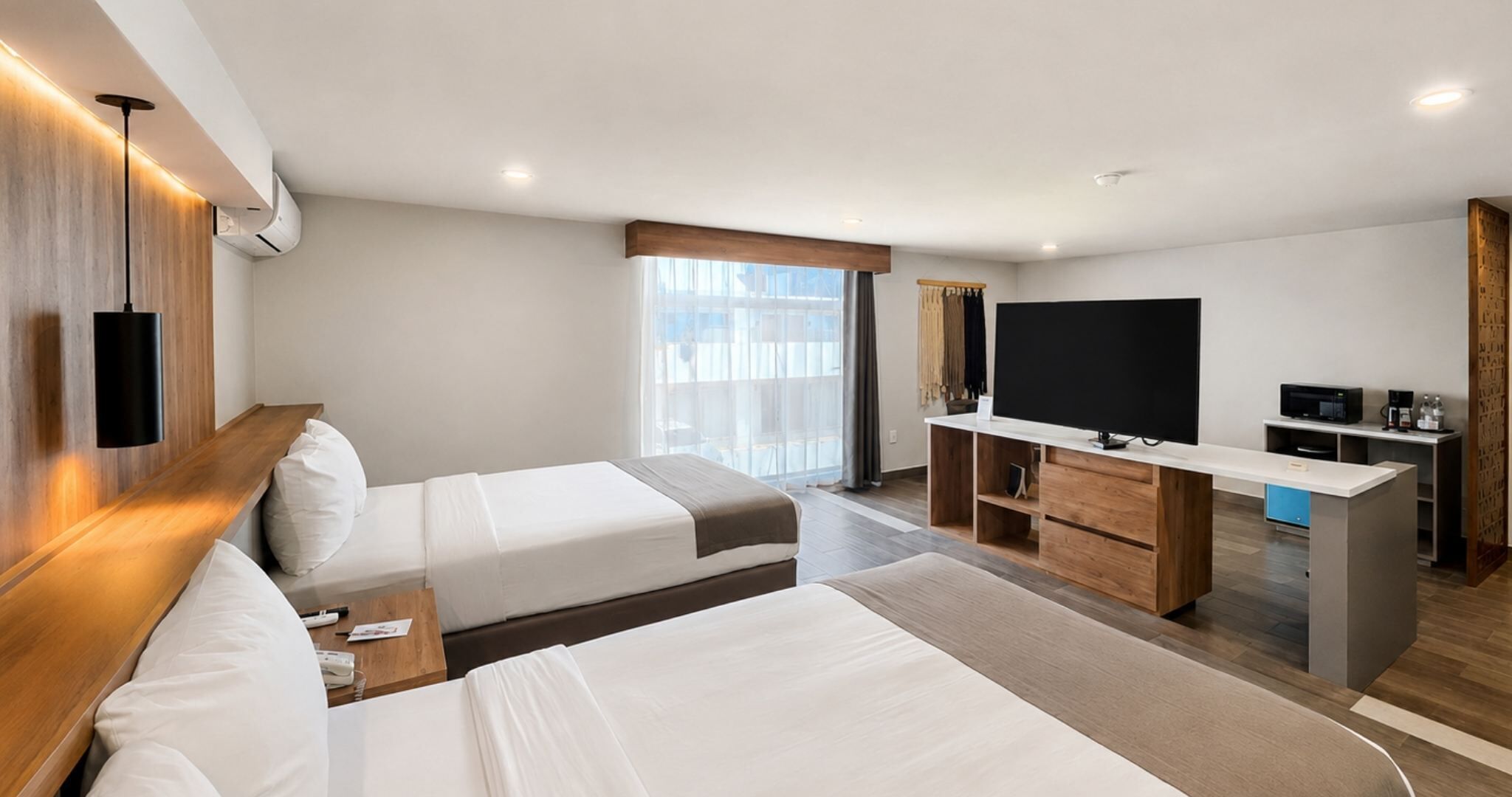 A hotel room with two beds, a TV, a desk, and a minibar.
