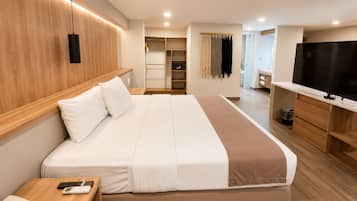 A hotel room with a large bed, a TV, a desk, and a wardrobe.