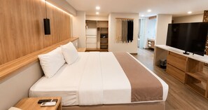 A hotel room with a large bed, a TV, a desk, and a wardrobe.