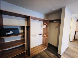 Un armario vestidor con repisas de madera, barra para colgar ropa y un espacio de almacenamiento.
