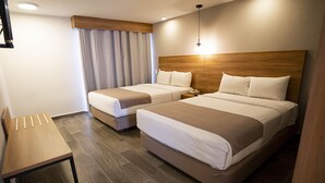 Una habitación de hotel con dos camas, cabecero de madera, un escritorio y una cortina.