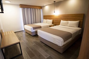 Ein Hotelzimmer mit zwei Betten, einem hölzernen Kopfteil, einem Schreibtisch und einem Vorhang.