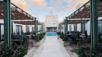 A corridor leading to a pool area with seating and planters.