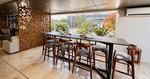 A modern dining area with a long table, six wooden chairs, and a decorative wooden partition.