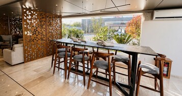 Un comedor moderno con una mesa larga, seis sillas de madera y un separador decorativo de madera.