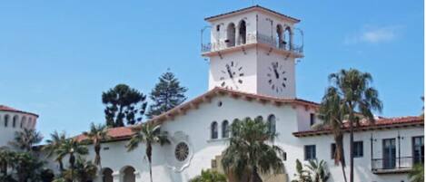 A historic courthouse with a clock tower, surrounded by palm trees and a well-maintained lawn.