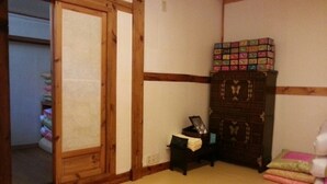 A traditional Japanese room with tatami flooring, a sliding door, a dark wooden cabinet, and a small table with a lamp. - Hyosunjae Hanok Guesthouse (Seoul)