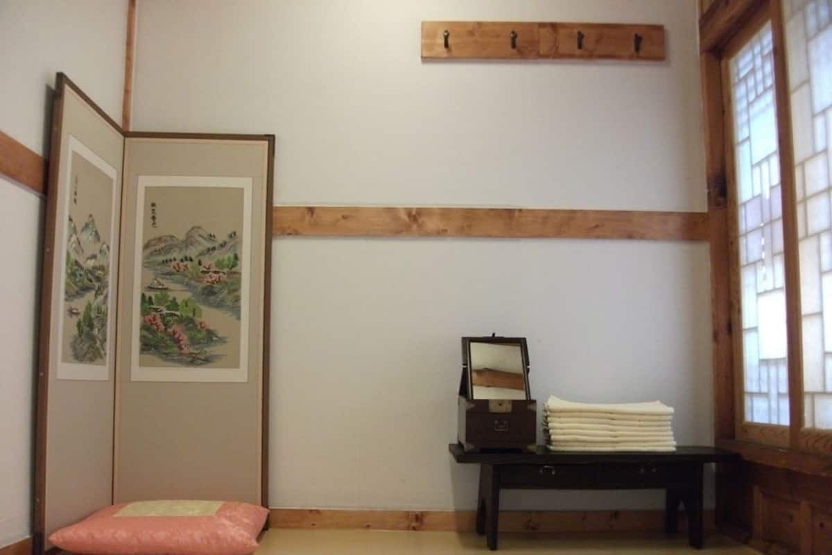 Une pièce de style japonais traditionnel, avec un sol recouvert de tatamis, un paravent en papier de riz (shoji), un petit bureau en bois doté d’un miroir et un coussin.