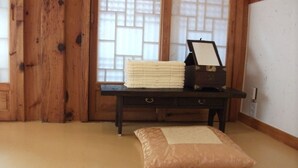A tatami mat room with a dark wooden table, a cushion, and a framed item on the table. - Hyosunjae Hanok Guesthouse (Seoul)