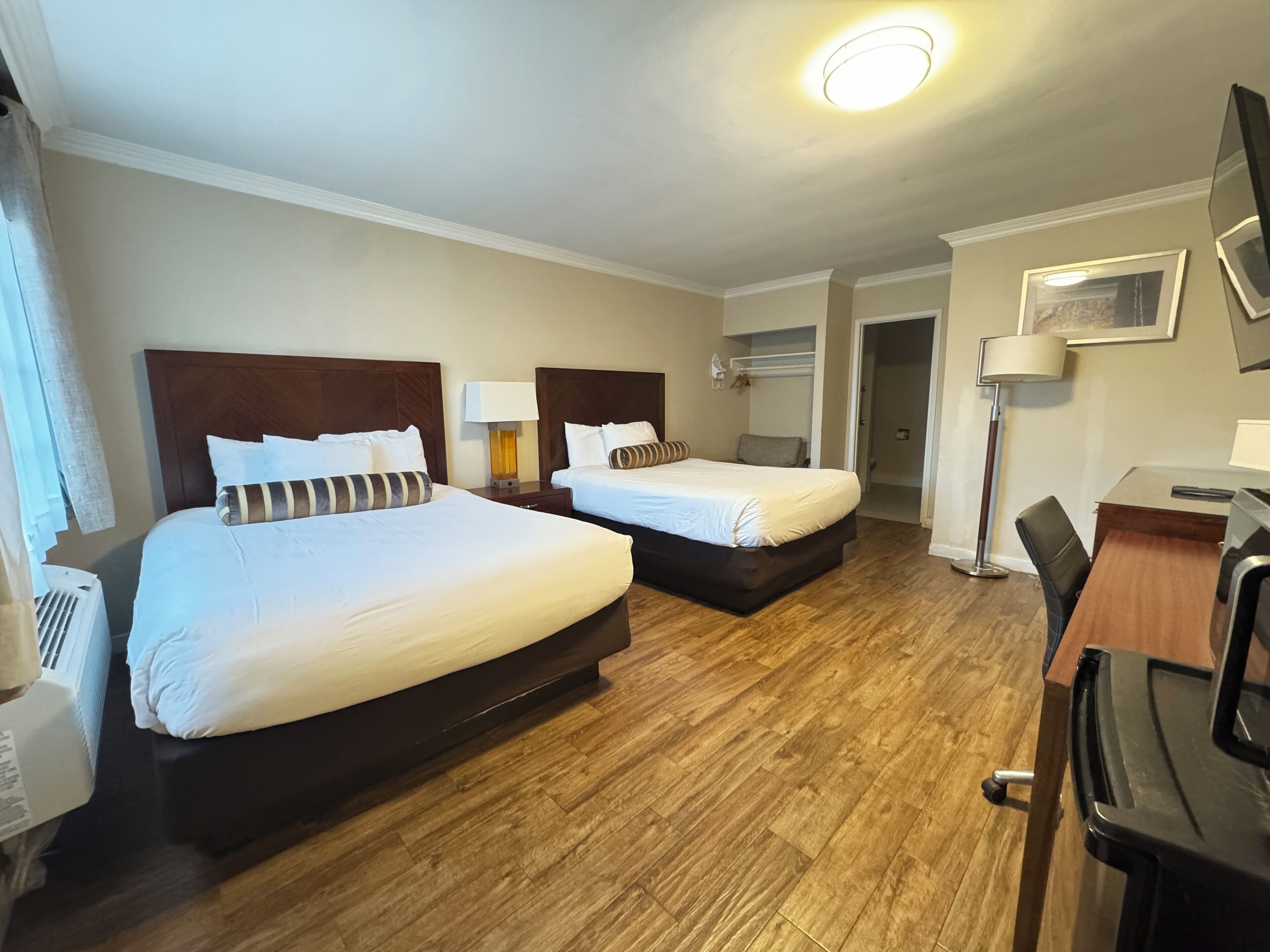 Ett hotellrum med två sängar, ett skrivbord och en stol.