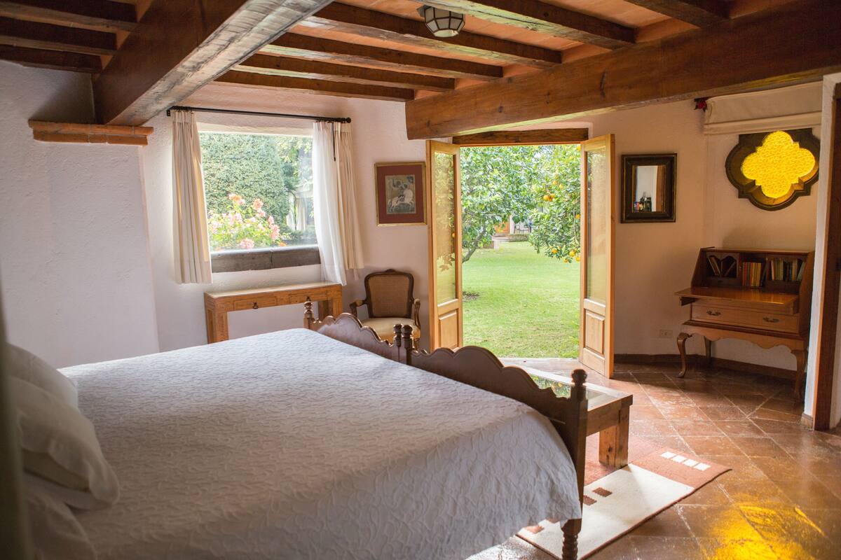 Un dormitorio con cama, una silla, un escritorio y una estantería.