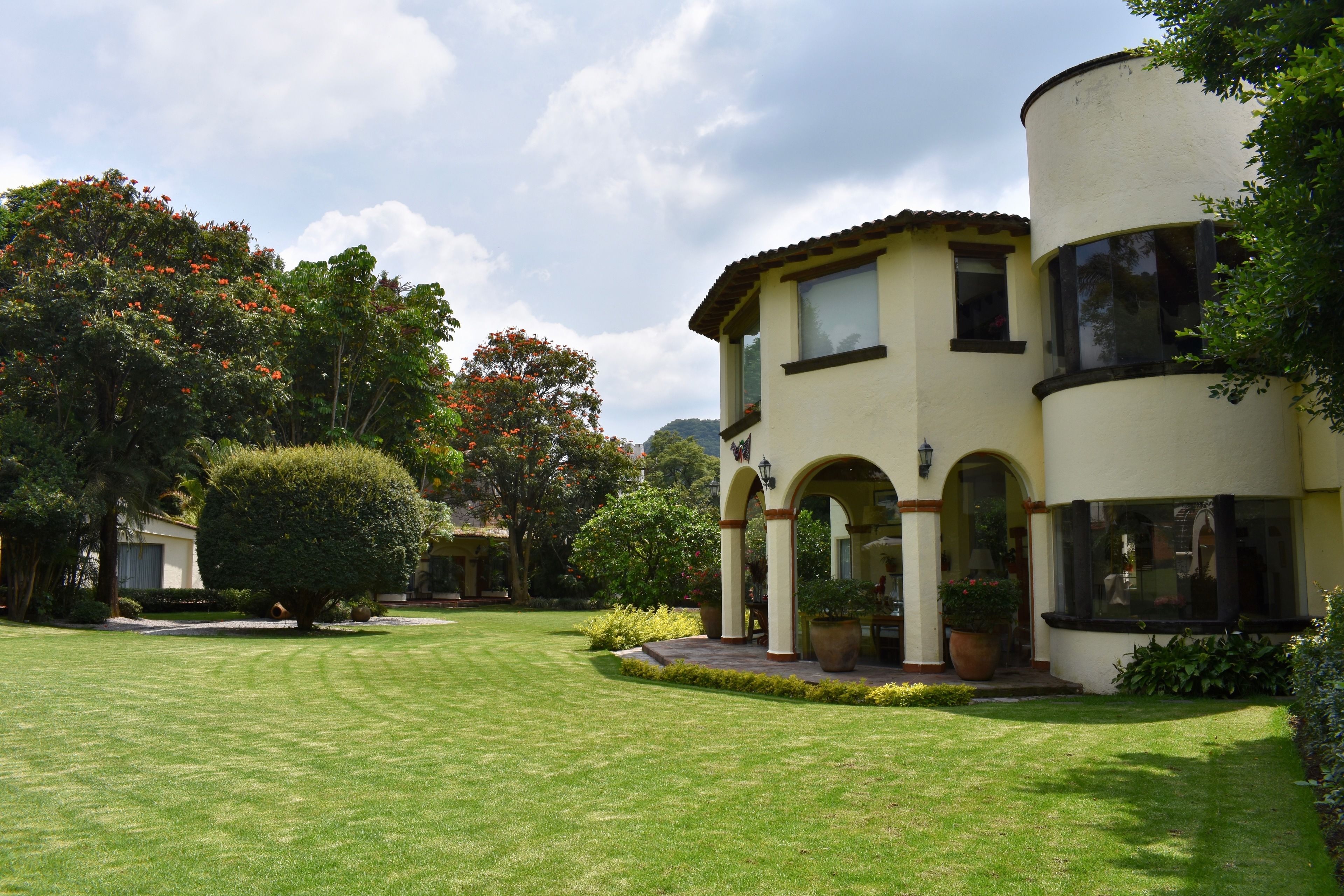 A two-story building with a courtyard, featuring a large arched entrance and potted plants.