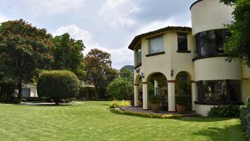 A two-story building with a courtyard, featuring a large arched entrance and potted plants.