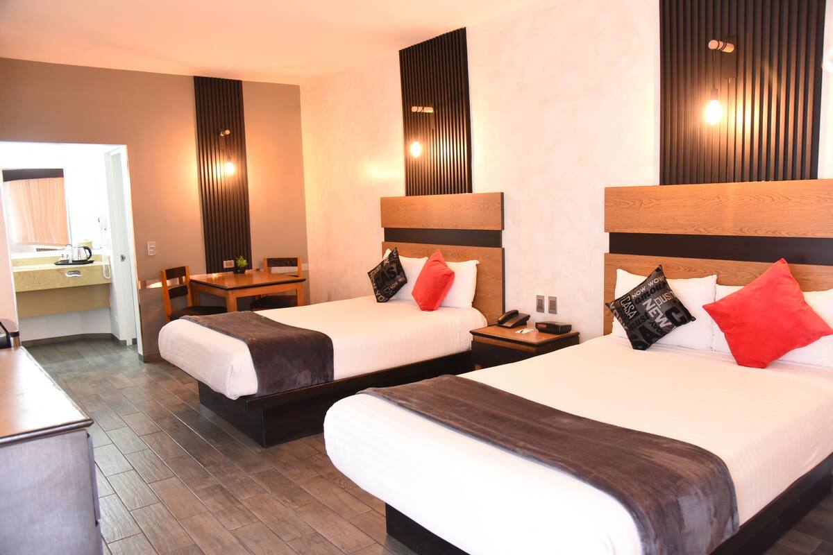 A hotel room with two beds, a desk, and a chair.