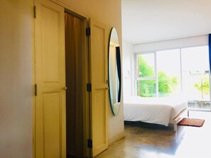 A bedroom with a bed, a large window, and a wardrobe. - NY TH Hotel (Si Racha)