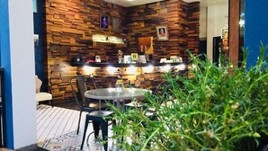 A cozy indoor seating area with a wooden wall, a round table, and chairs. - NY TH Hotel (Si Racha)