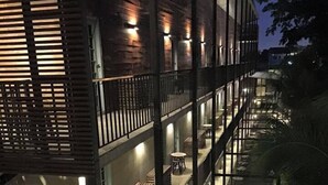A multi-story building with balconies, outdoor seating, and a staircase. - NY TH Hotel (Si Racha)