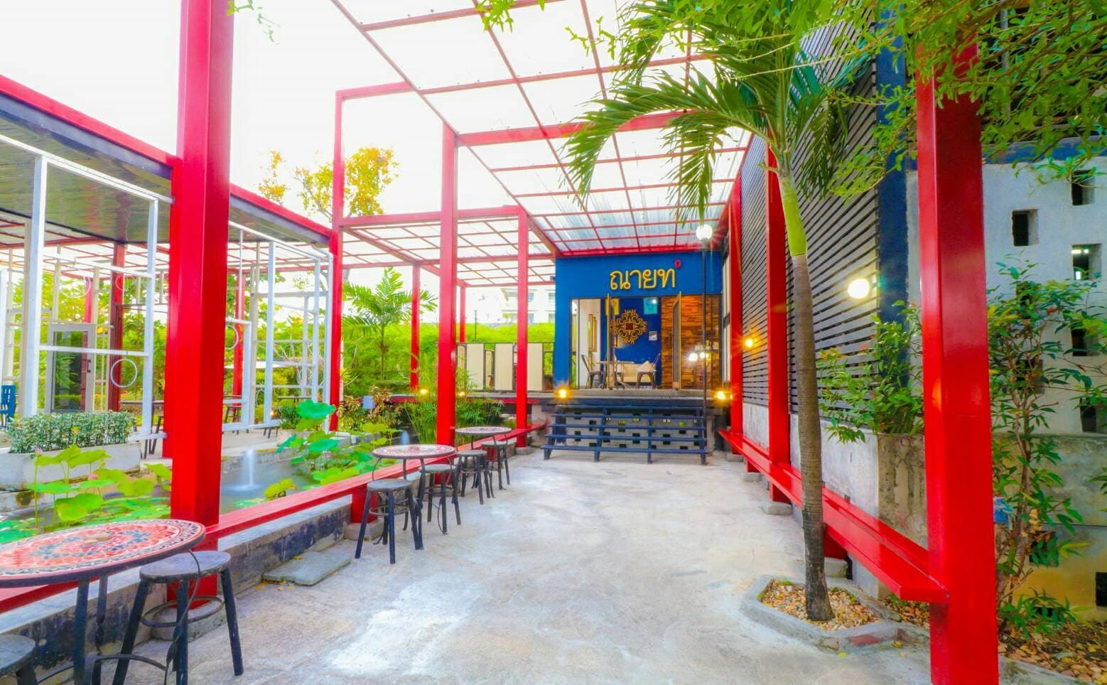 An outdoor cafe area with red structural elements, tables, and chairs.