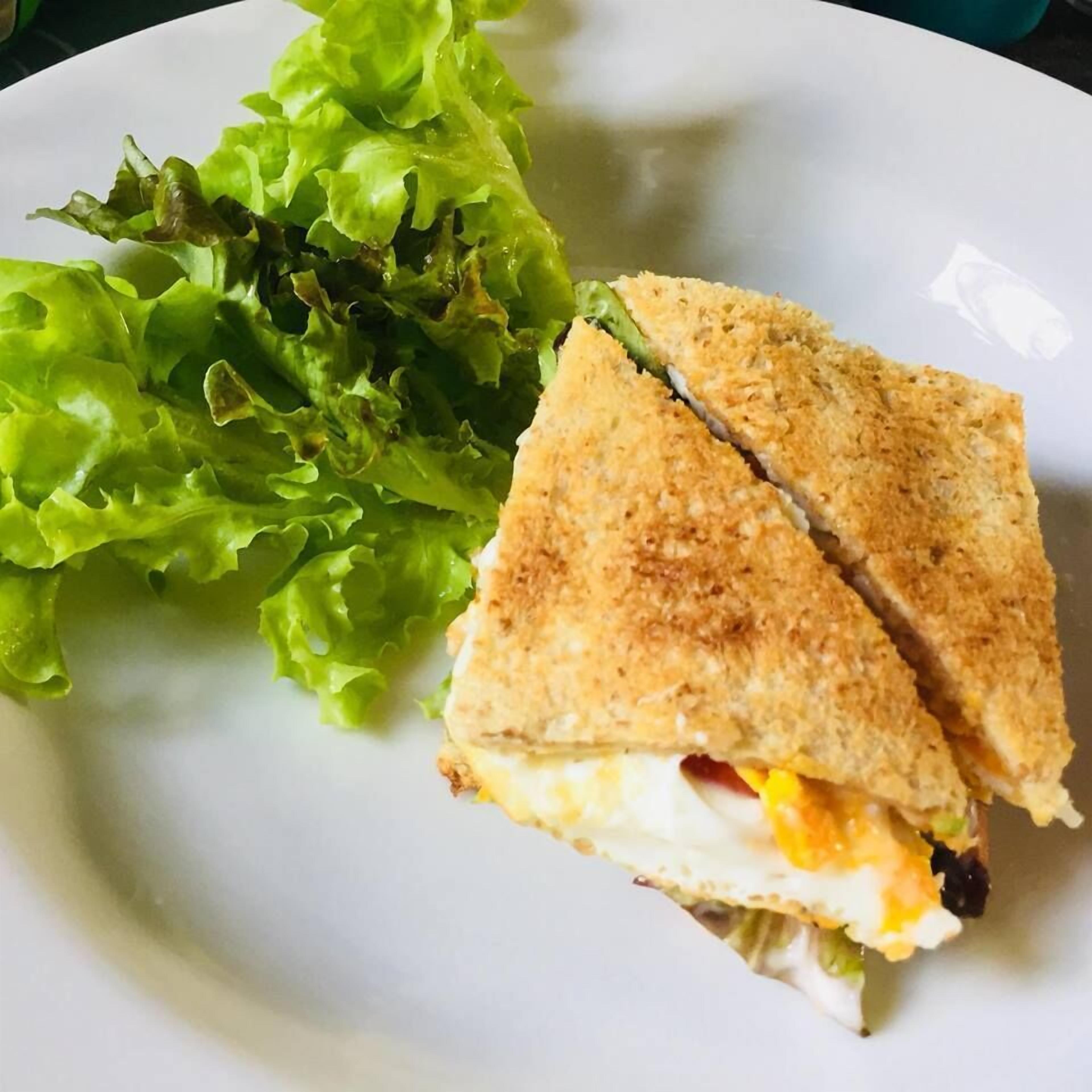 Un sándwich cortado por la mitad con lechuga al lado.