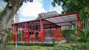A modern hotel structure with a red frame, outdoor seating, and a view of the hotel building in the background. - NY TH Hotel (Si Racha)