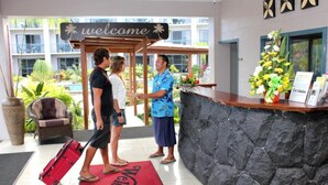 Zona de recepción con un cartel que dice 'Welcome', un mostrador de recepción y una alfombra roja con el texto 'Welcome'.