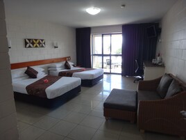 A hotel room with two beds, a sofa, a TV, and a balcony with curtains.