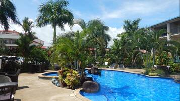 A pool area with lounge chairs and a building in the background.
