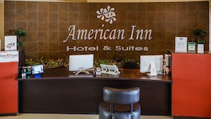 A reception desk at American Inn Hotel & Suites with a computer, a cash register, and a plant. - American Inn Hotel & Suites Delicias (Delicias)
