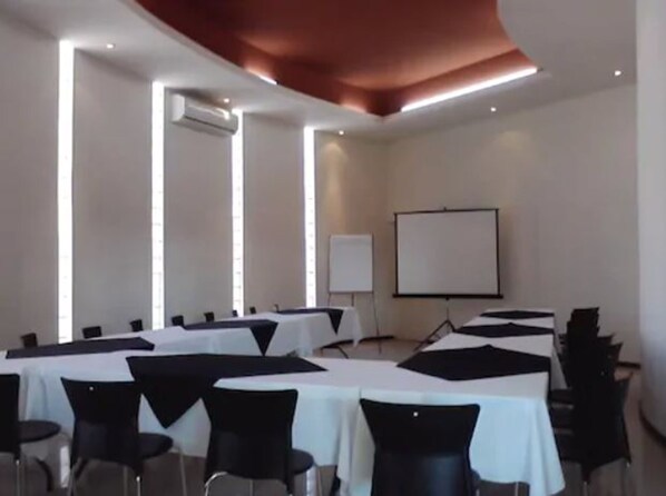 A conference room with tables and chairs, a whiteboard, and a projector screen.