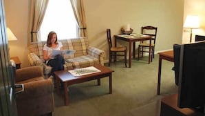 Una sala de estar acogedora con un sofá de cuadros, una mesa de centro de madera, una mesa de comedor con sillas y un televisor.