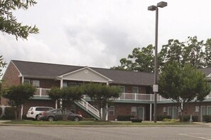 A two-story motel with a brick facade, a covered front porch, and a parking lot.