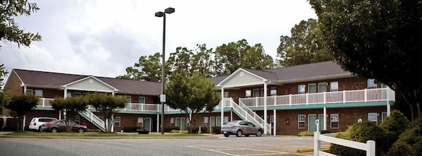 A motel with two-story buildings, a parking lot, and a streetlight.