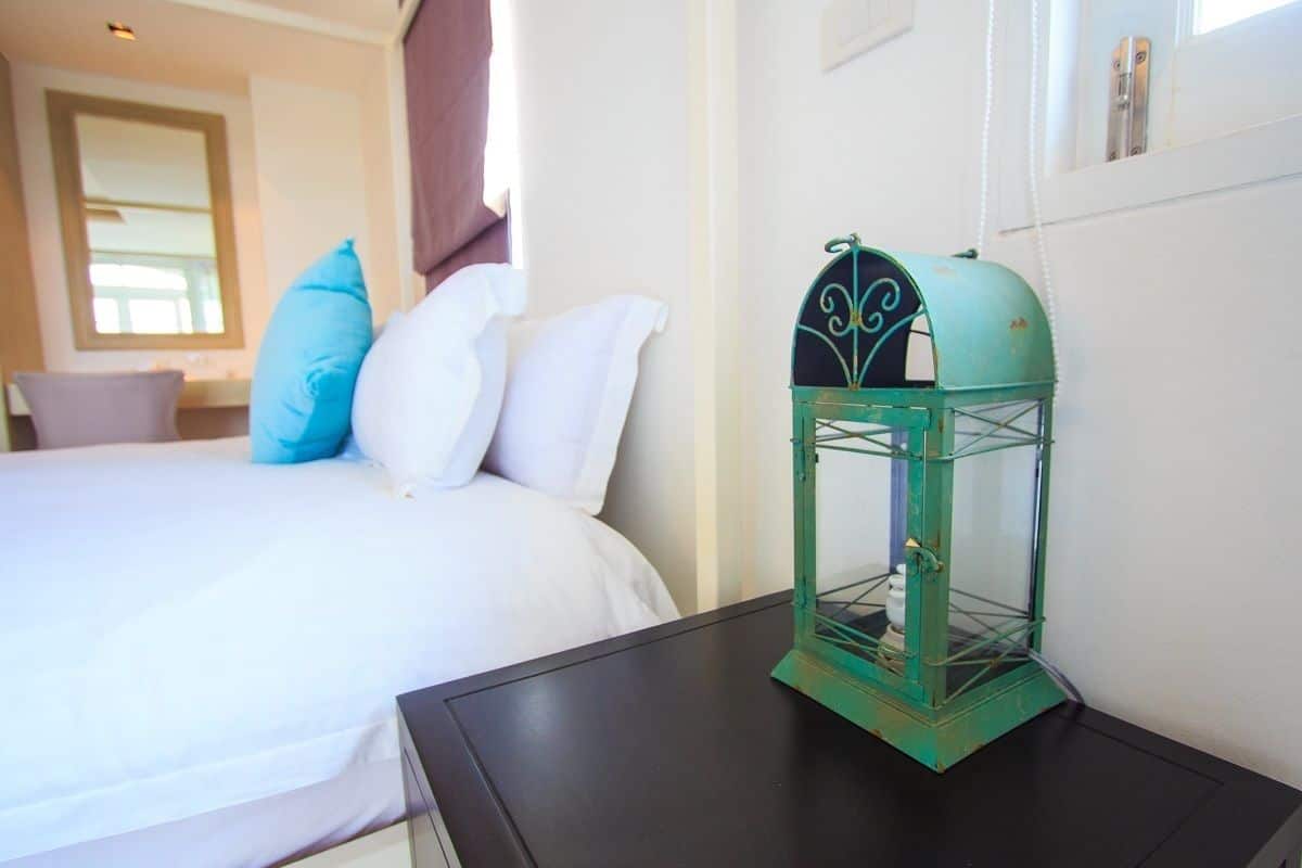 Una habitación de hotel con cama, almohadas, una mesita de noche y un farol verde.